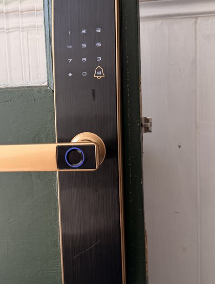 Example photo: a smart lock on a front door seen from outside, close enough to show the keypad, handle and fingerprint reader.